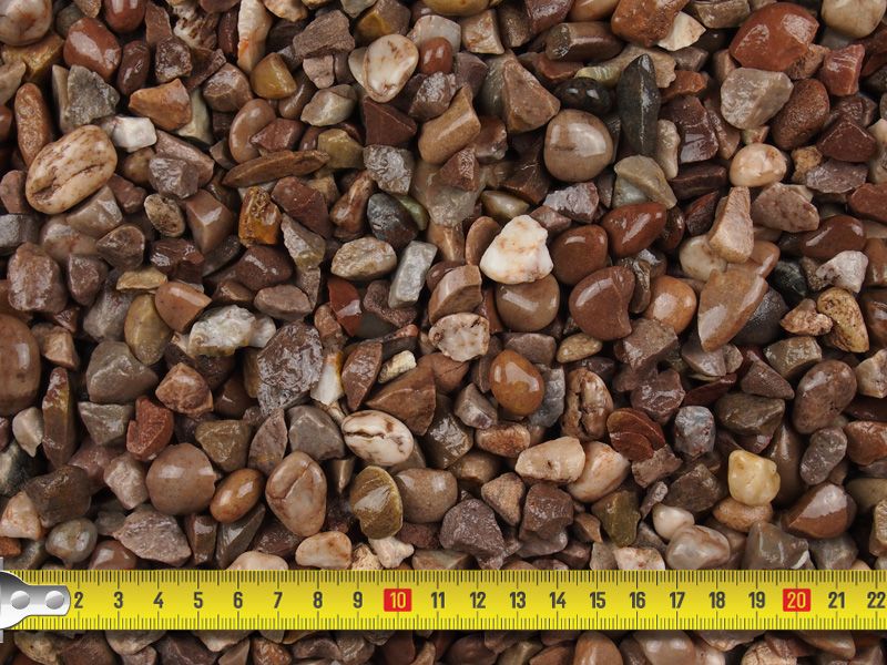 Close-up of mixed brown decorative pebbles with a yellow measuring tape