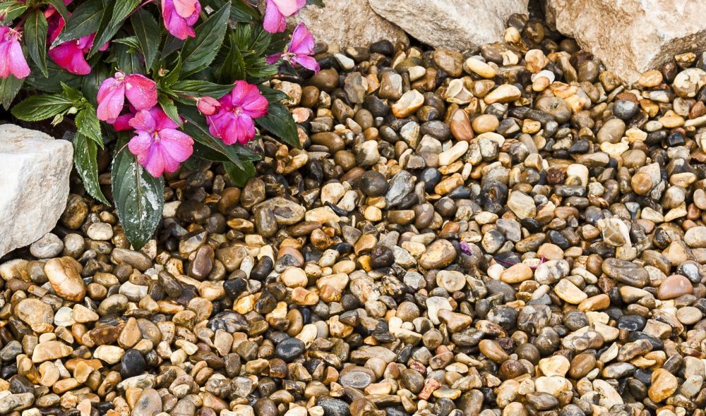A close-up image of Lomond gravel 20mm, showing angular-shaped stones in brown, grey, and silver colors.