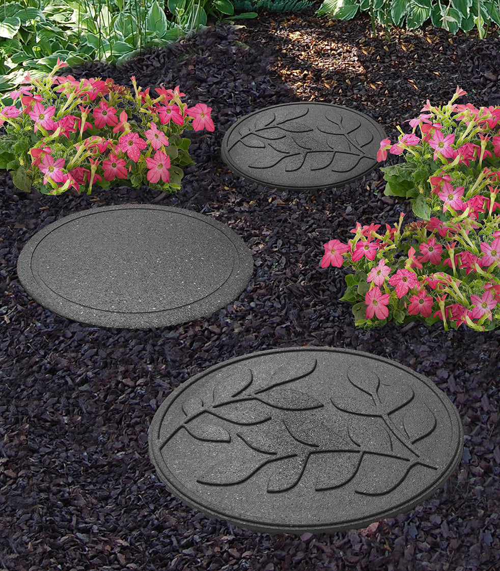 Decorative Grey round stepping stones with leaf patterns in a garden path surrounded by flowers.