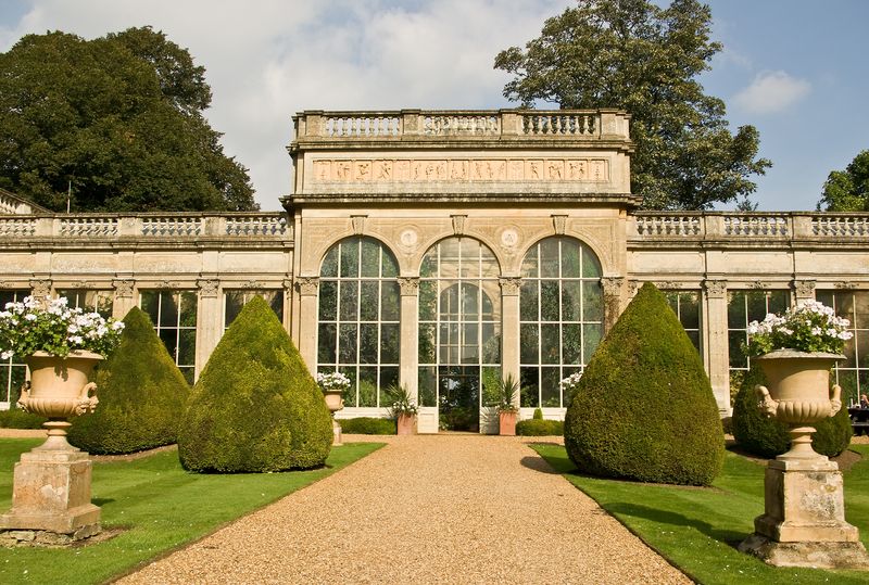 A garden pathway laid with Cotswold gold gravel, with a building and neatly trimmed hedges in the background.