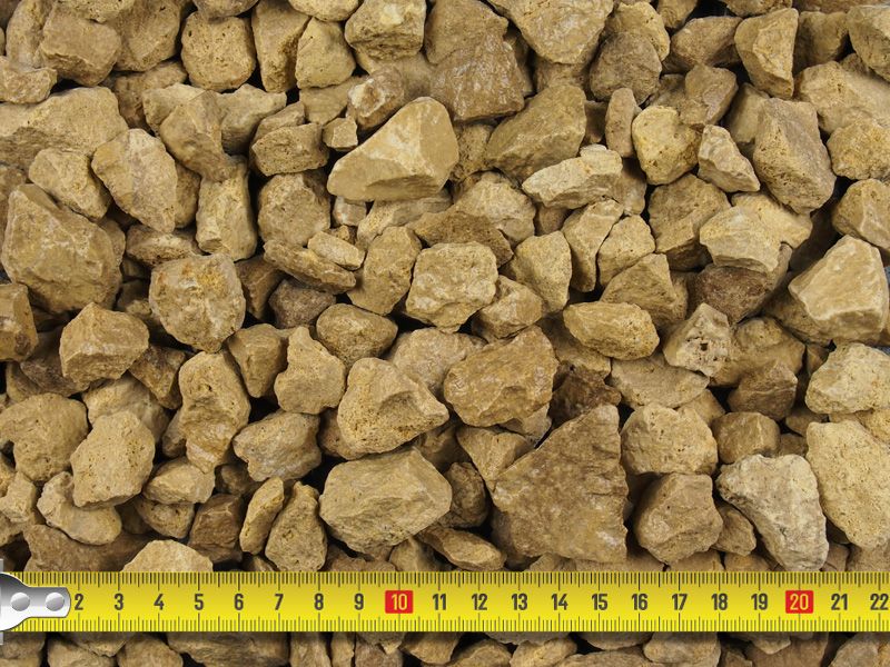 Close-up of cotswold gold stones with a measuring tape showing their size.