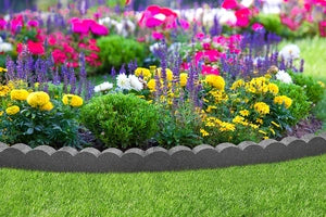 A flexible gray, scalloped garden border strip made from recycled tyre rubber installed around a bed of colorful flowers