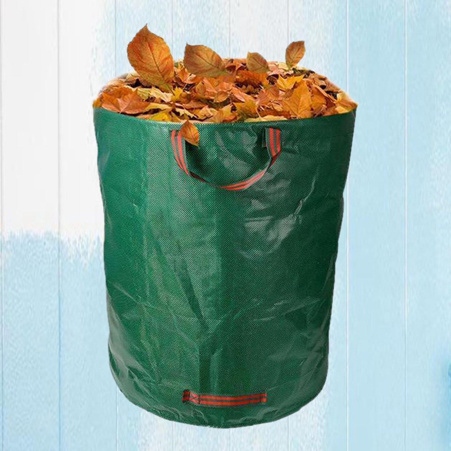 Green garden waste bag filled with dry autumn leaves.