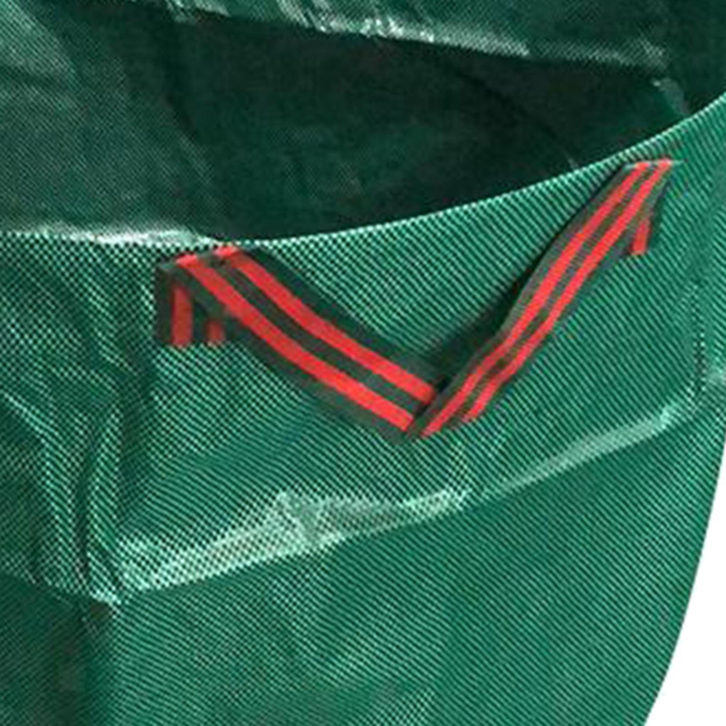 Close-up of a green garden waste bag with red and black striped handles.