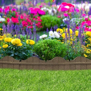 A vibrant flower garden bordered with a terracotta brown color stone edging and green grass.