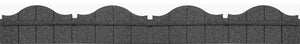 A section of a gray stone garden border with a scalloped, wave-like top, designed for edging garden beds or lawns.