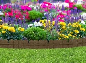 A vibrant flower garden with a mix of colorful flowers, bordered by a terracotta brown stone edging and green grass.